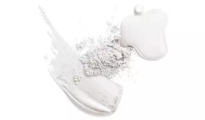 A flat lay of various textures featuring a white powder, a creamy white smear, and a glossy droplet resembling a cosmetic product.