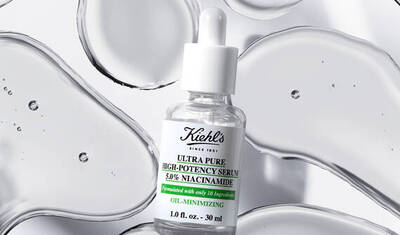 A dropper bottle of Kiehl's Ultra Pure High-Potency Serum with 5% Niacinamide, surrounded by scattered drops of clear liquid on a white background.